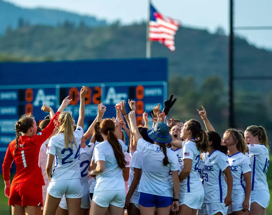 athletes in a huddle with hands up